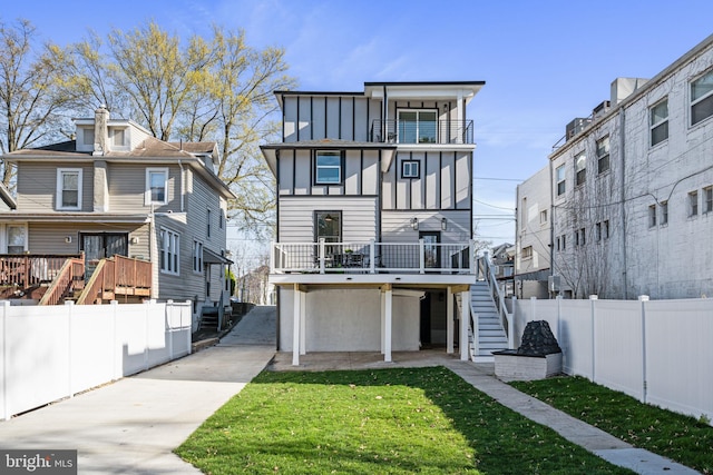 rear view of property with a wooden deck, stairway, a yard, board and batten siding, and fence