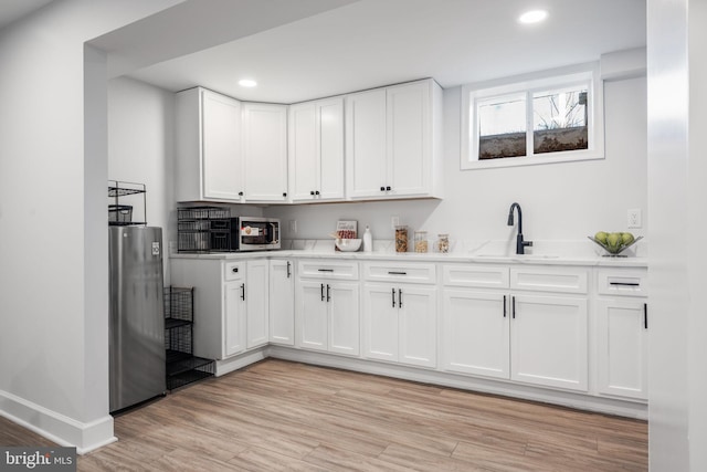 kitchen with white cabinetry, appliances with stainless steel finishes, and light hardwood / wood-style flooring