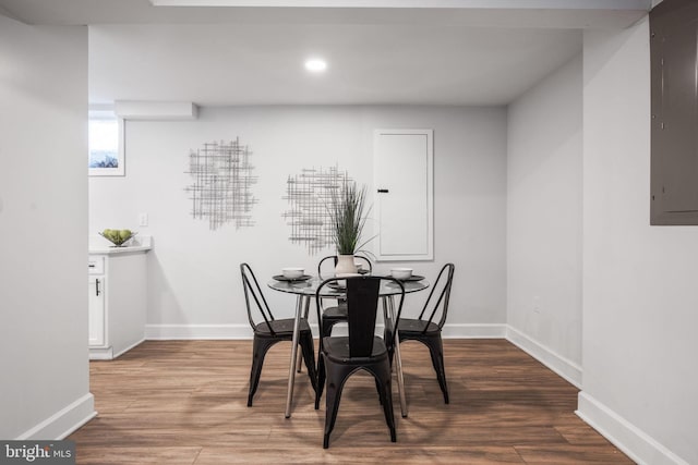 dining room featuring electric panel, wood finished floors, and baseboards
