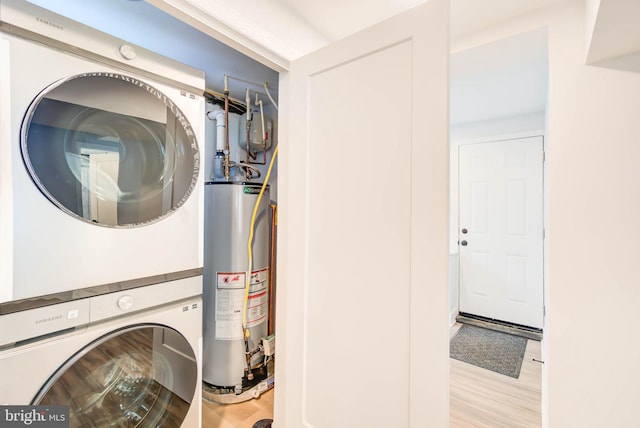 laundry area with wood finished floors, gas water heater, laundry area, and stacked washer / drying machine