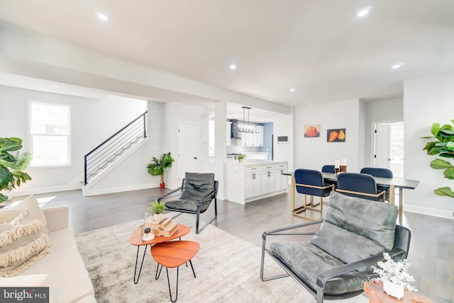 living area with recessed lighting, wood finished floors, and stairs