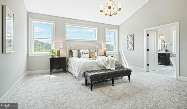 carpeted bedroom featuring ensuite bathroom, vaulted ceiling, and an inviting chandelier