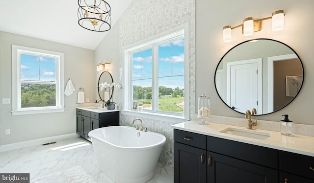 bathroom featuring vanity, vaulted ceiling, a notable chandelier, and a tub to relax in