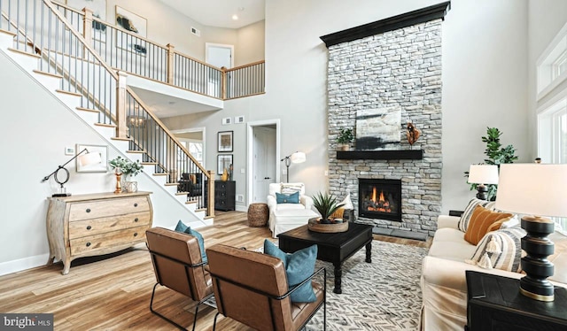 living room featuring a towering ceiling, hardwood / wood-style floors, and a fireplace