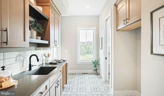 kitchen with dark stone countertops, light tile patterned flooring, decorative backsplash, and sink