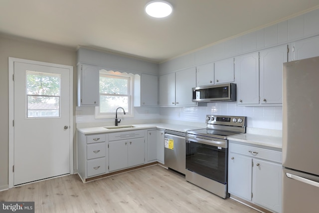 kitchen featuring white cabinetry, stainless steel appliances, sink, and light wood-type flooring