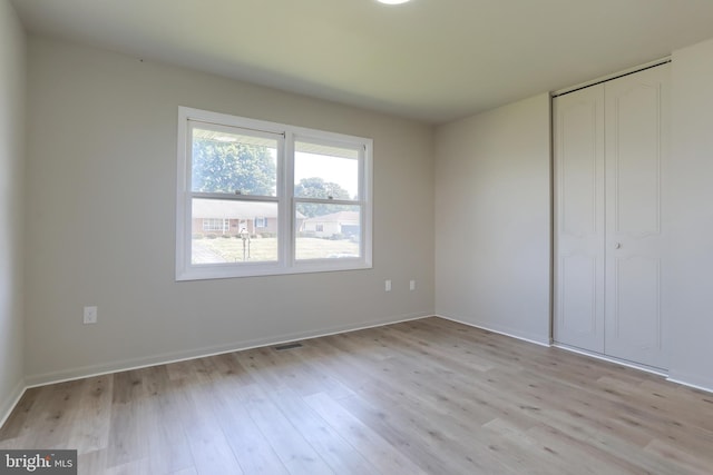 unfurnished bedroom with light hardwood / wood-style flooring and a closet