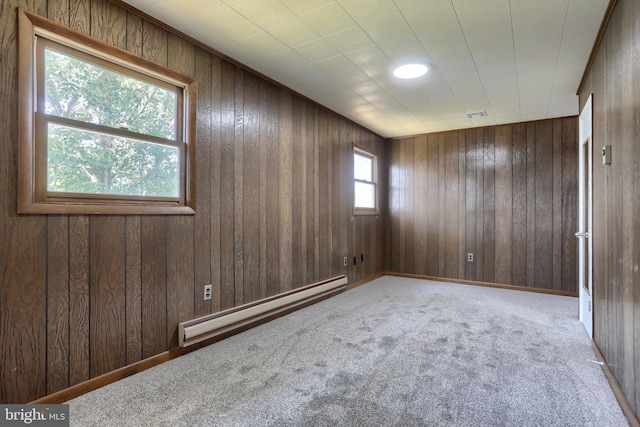 carpeted empty room featuring baseboard heating and wood walls