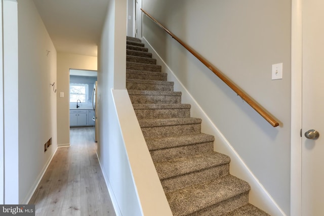 staircase featuring sink and wood-type flooring