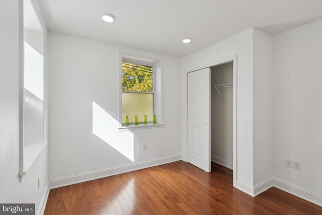 unfurnished bedroom with a closet and dark wood-type flooring