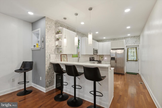 kitchen featuring appliances with stainless steel finishes, kitchen peninsula, white cabinets, and dark hardwood / wood-style flooring