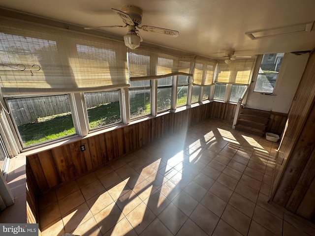 unfurnished sunroom featuring ceiling fan and a wealth of natural light