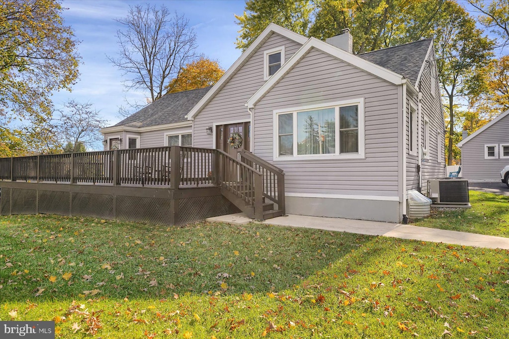 rear view of house with central AC, a lawn, and a deck