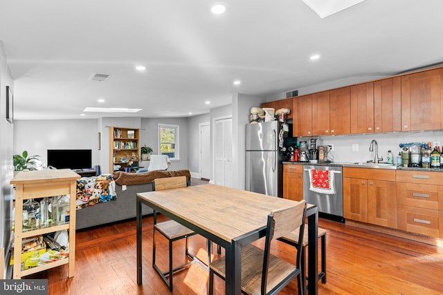 kitchen featuring hardwood / wood-style flooring, sink, stainless steel appliances, and a skylight