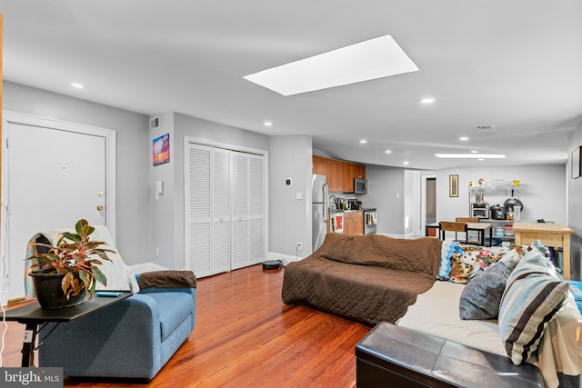 living room with a skylight and light hardwood / wood-style flooring