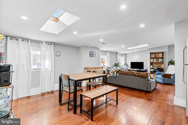 dining space featuring wood-type flooring and a skylight