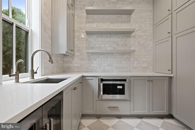 kitchen with a wealth of natural light, sink, gray cabinetry, and oven