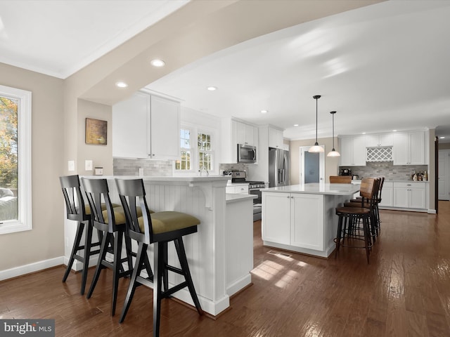 kitchen with appliances with stainless steel finishes, a breakfast bar, white cabinets, and kitchen peninsula