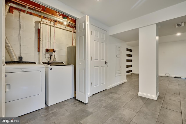 clothes washing area with washer and dryer and light tile patterned floors