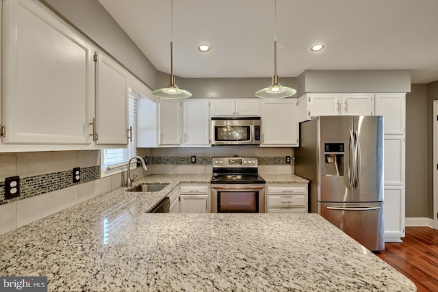 kitchen with appliances with stainless steel finishes, sink, pendant lighting, and white cabinets