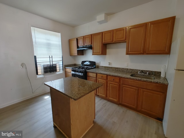 kitchen featuring black gas range, a kitchen island, sink, light wood-type flooring, and white refrigerator