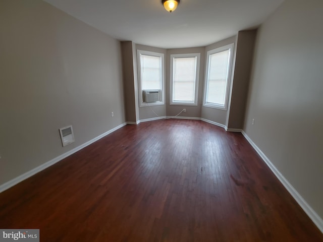 empty room featuring cooling unit and dark wood-type flooring