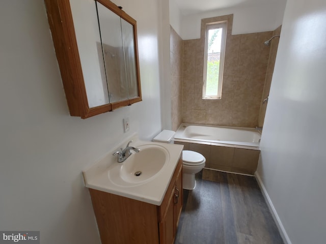 full bathroom with vanity, tiled shower / bath combo, hardwood / wood-style flooring, and toilet