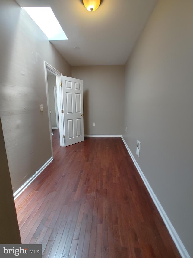 spare room with dark hardwood / wood-style floors and a skylight