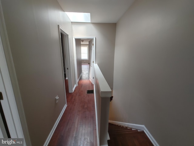 hall featuring dark hardwood / wood-style floors and a skylight