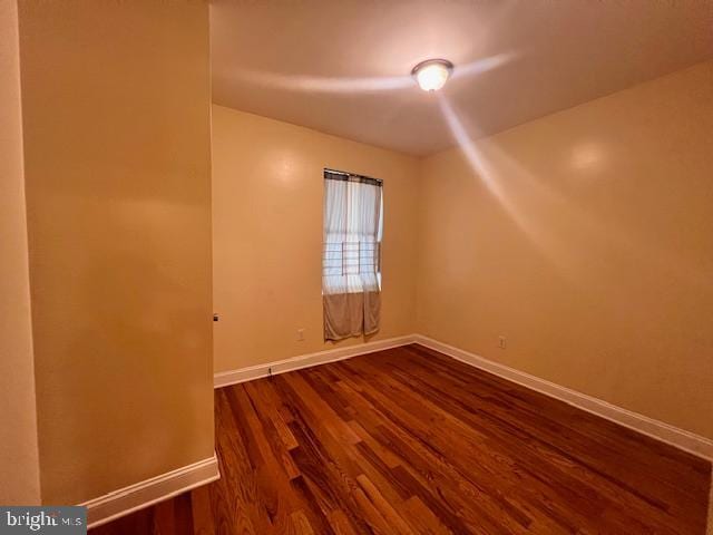 unfurnished room with dark hardwood / wood-style flooring