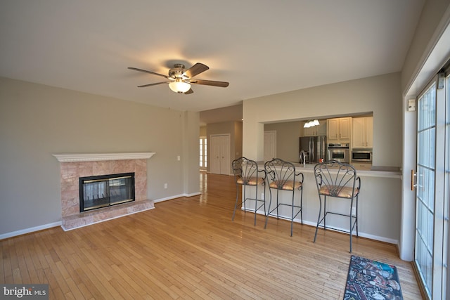 unfurnished living room featuring a fireplace, light hardwood / wood-style floors, and ceiling fan