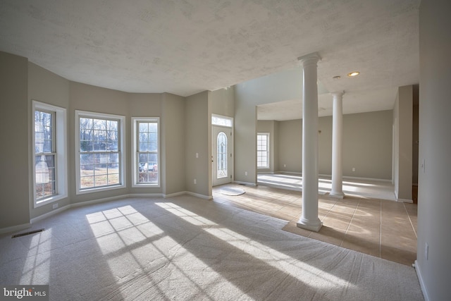 interior space featuring decorative columns, a wealth of natural light, and light colored carpet