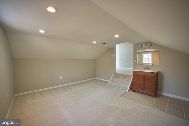 additional living space with light carpet, sink, and lofted ceiling