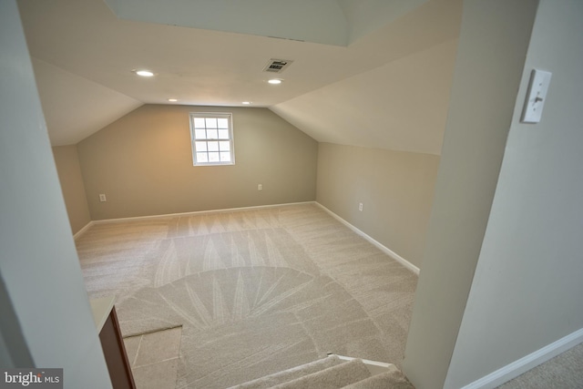 bonus room with light colored carpet and vaulted ceiling