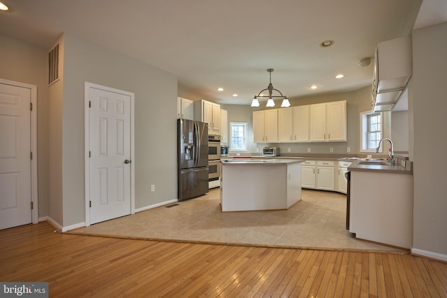 kitchen featuring a kitchen island, light hardwood / wood-style flooring, pendant lighting, white cabinets, and appliances with stainless steel finishes