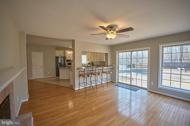 unfurnished living room featuring ceiling fan, a tile fireplace, and light hardwood / wood-style flooring