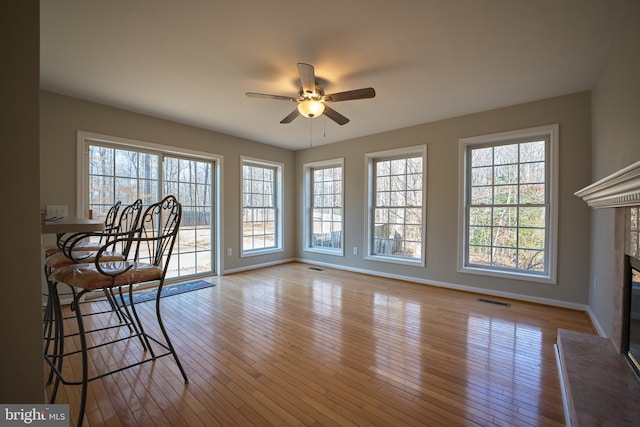 living room with ceiling fan, a fireplace, and light hardwood / wood-style flooring