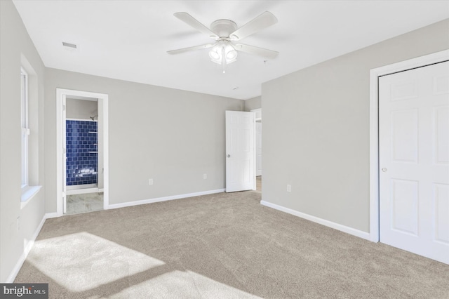 unfurnished bedroom featuring connected bathroom, light colored carpet, and ceiling fan