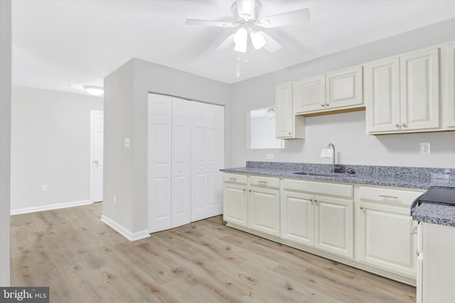 kitchen with light hardwood / wood-style floors, light stone countertops, sink, and ceiling fan