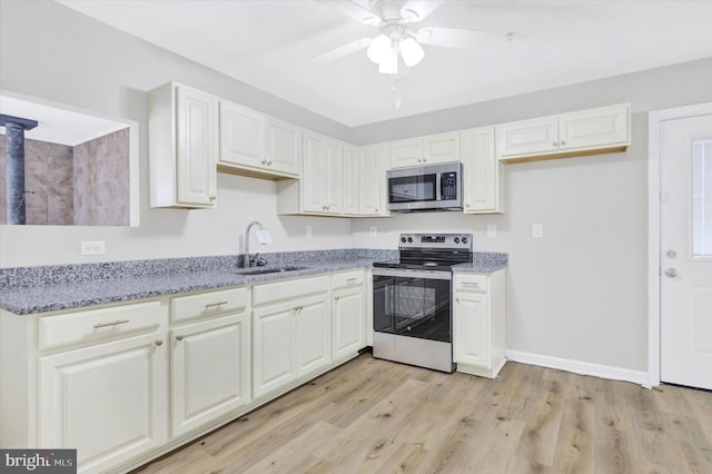 kitchen with sink, stainless steel appliances, white cabinetry, and light hardwood / wood-style flooring