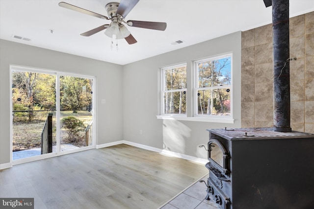 interior space featuring light hardwood / wood-style floors, a healthy amount of sunlight, and a wood stove