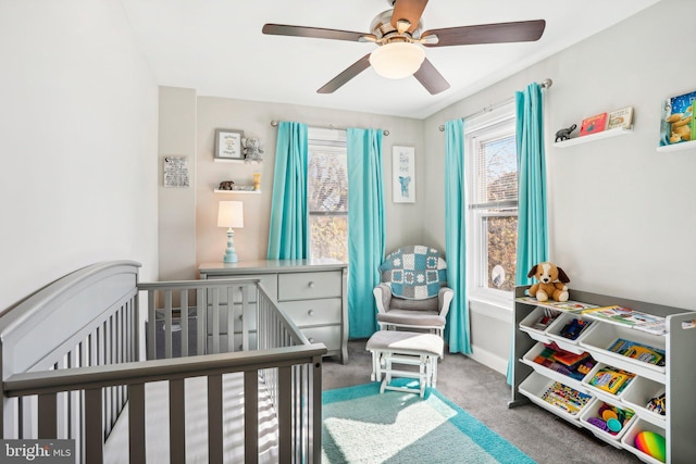 bedroom featuring a nursery area, ceiling fan, and carpet