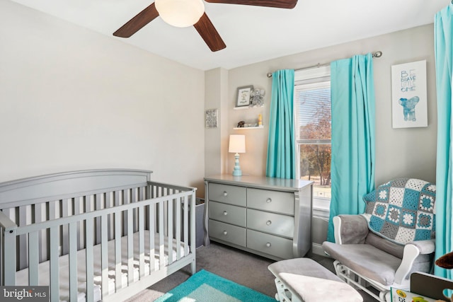 carpeted bedroom featuring multiple windows, a nursery area, and ceiling fan