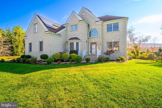 view of front of home featuring brick siding, roof mounted solar panels, and a front yard