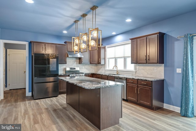 kitchen with a center island, light hardwood / wood-style flooring, ventilation hood, pendant lighting, and appliances with stainless steel finishes