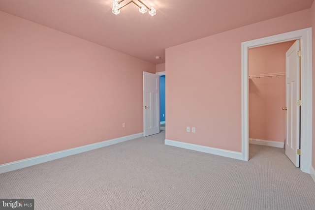 unfurnished bedroom featuring light colored carpet, a spacious closet, and a closet