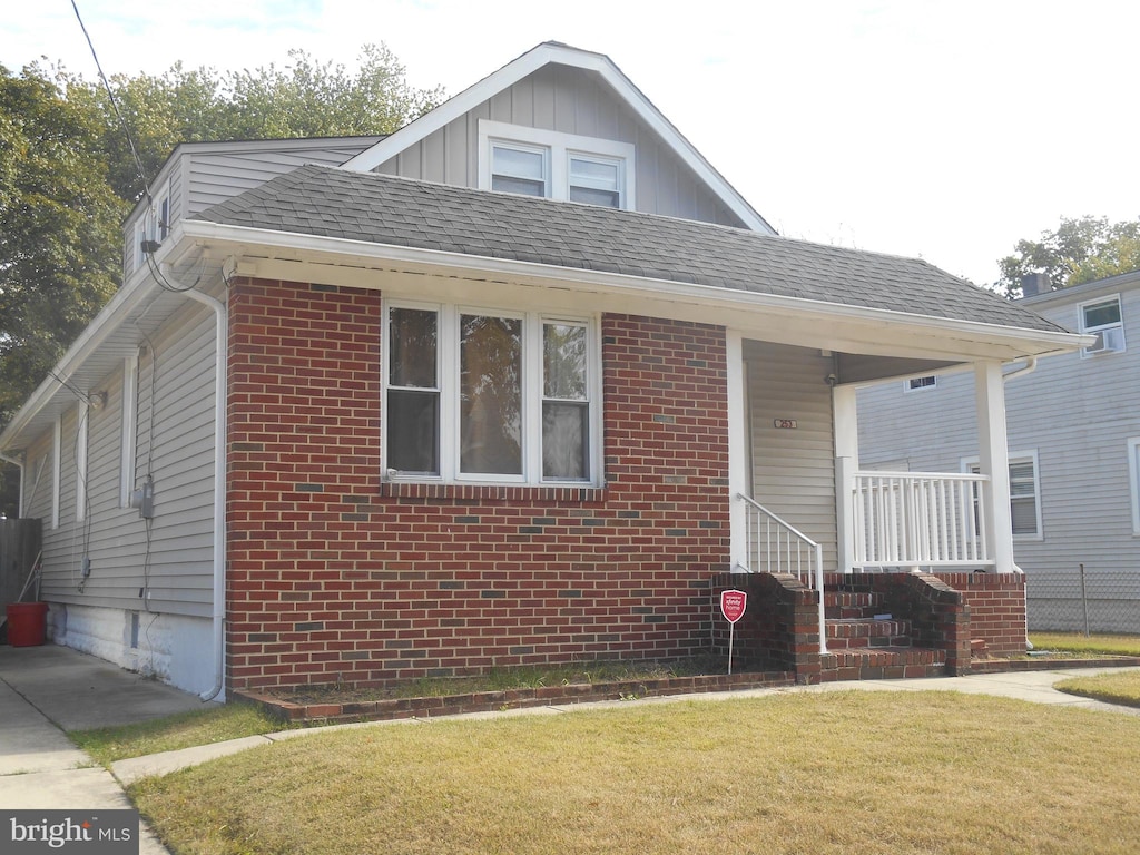 bungalow-style home with covered porch and a front yard