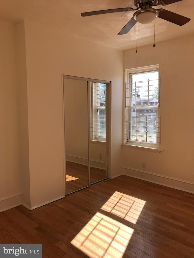 unfurnished bedroom with ceiling fan, dark wood-type flooring, and a closet