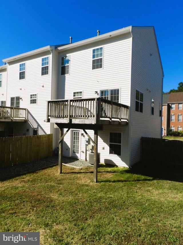 back of house featuring central AC unit, a wooden deck, and a lawn