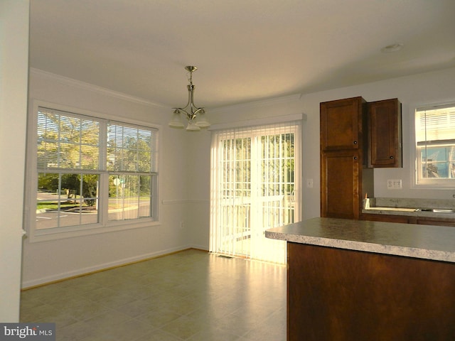 unfurnished dining area with crown molding, a healthy amount of sunlight, and an inviting chandelier